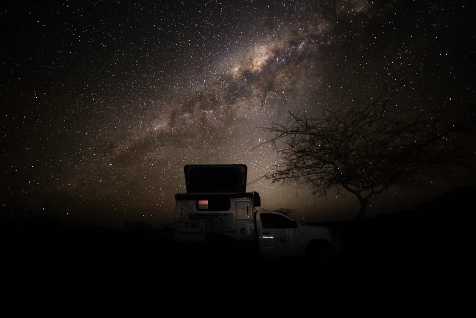 Camper als Silhouette unter der Milchstraße.