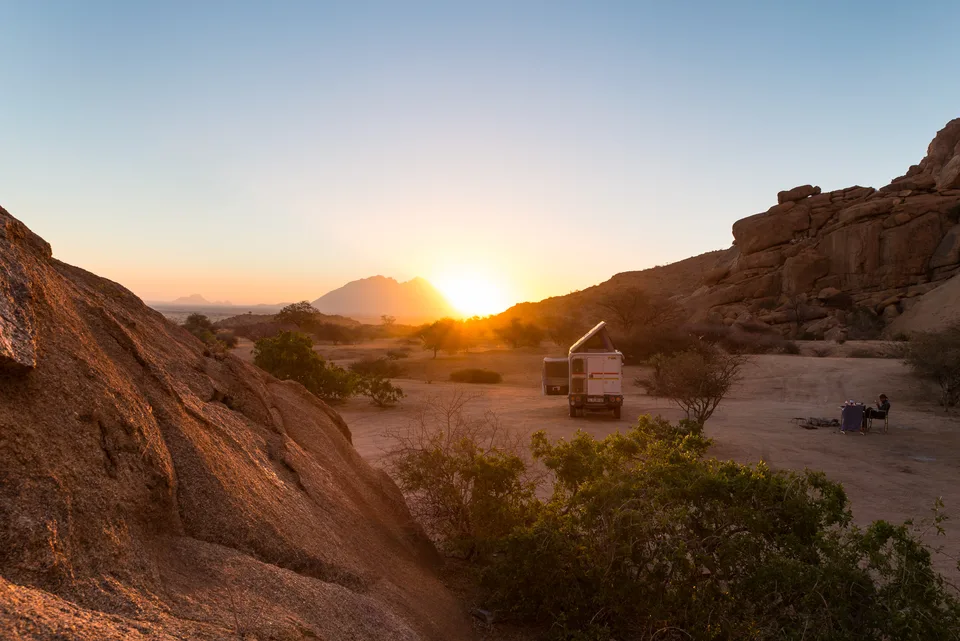 Kleiner Camper zwischen Felsen bei Sonnenuntergang.