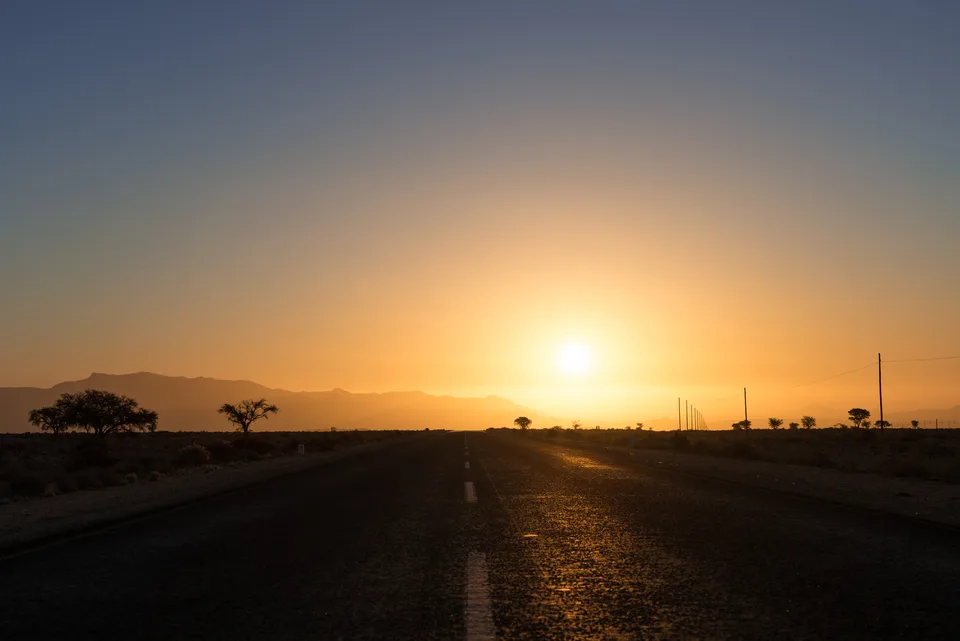 Gerade Straße im warmen Licht der tief stehenden Sonne.